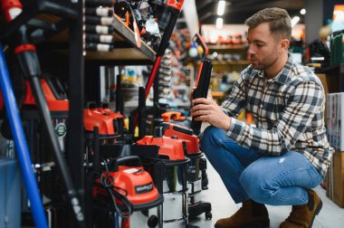 Bir adam hırdavatçıdan endüstriyel elektrik süpürgesi seçiyor..