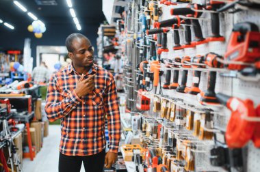Afrikalı bir Amerikalı hırdavatçıdan elektrikli bir alet seçiyor..