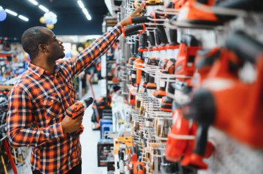 Afrika kökenli Amerikalı bir adam elektrikli tornavida tutuyor ve onu seçiyor..