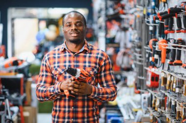 Afrika kökenli Amerikalı bir adam elektrikli tornavida tutuyor ve onu seçiyor..