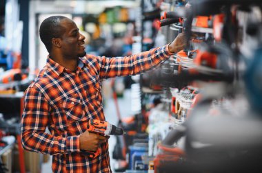 Afrika kökenli Amerikalı bir adam elektrikli tornavida tutuyor ve onu seçiyor..