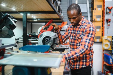 Afrikalı bir Amerikalı hırdavatçıdan elektrikli bir alet seçiyor..