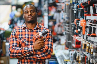 Afrika kökenli Amerikalı bir adam elektrikli tornavida tutuyor ve onu seçiyor..