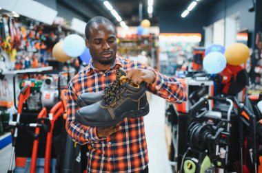 Bir hırdavatçıda çalışan Afrikalı Amerikalı inşaat için güvenli ayakkabı seçiyor..