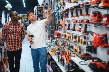 Matkap ya da tornavida almak. Nalburdaki bir danışman, erkek müşteriye yeni bir tornavida satın alınması konusunda tavsiyede bulunur..