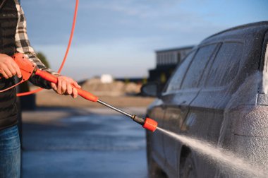 Araba yıkamada yıkanır, adam arabayı köpükle yıkar. Ayrıntılar.
