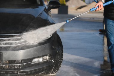 Bir adam arabasını oto yıkamada yıkıyor..