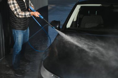 Bir adam arabasını oto yıkamada yıkıyor..
