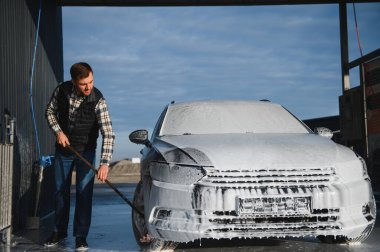 Araba yıkamada yıkanır, adam arabayı köpükle yıkar. Ayrıntılar.