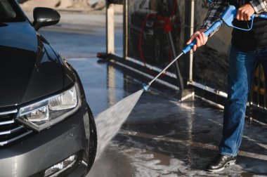 Bir adam arabasını oto yıkamada yıkıyor..