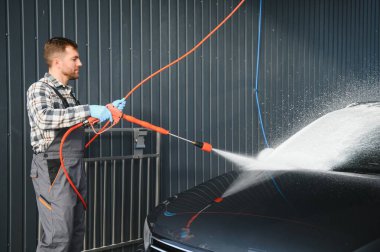 Erkek işçi araba yıkama servisi. Araba yıkama istasyonu yüksek basınçlı su. Çalışanlar bir aracı profesyonel olarak temizler.