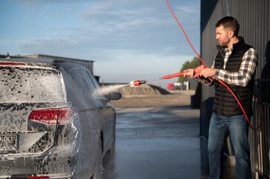 Araba yıkamada yıkanır, adam arabayı köpükle yıkar. Ayrıntılar.