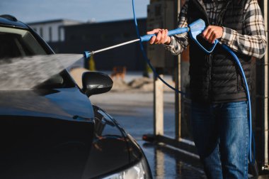 Bir adam arabasını oto yıkamada yıkıyor..