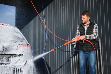 Araba yıkamada yıkanır, adam arabayı köpükle yıkar. Ayrıntılar.