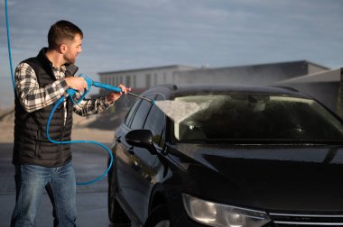 Bir adam arabasını oto yıkamada yıkıyor..