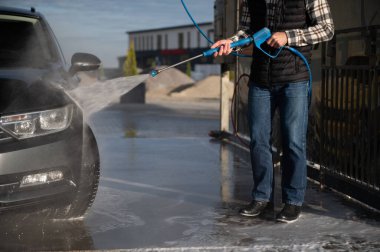 Bir adam arabasını oto yıkamada yıkıyor..