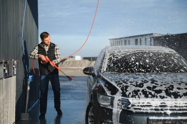 Araba yıkamada yıkanır, adam arabayı köpükle yıkar. Ayrıntılar.