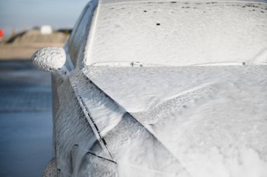 Beyaz köpüklü modern araba oto yıkamada yıkanır. Araba bakımı. Ayrıntılar.