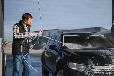 Bir adam arabasını oto yıkamada yıkıyor..