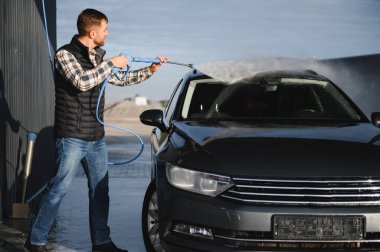 Bir adam arabasını oto yıkamada yıkıyor..