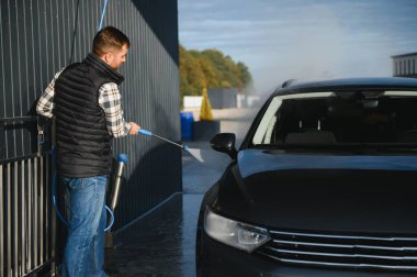 Bir adam arabasını oto yıkamada yıkıyor..