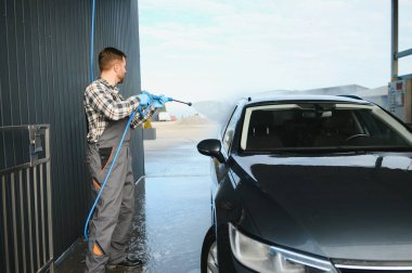 Erkek işçi araba yıkama servisi. Araba yıkama istasyonu yüksek basınçlı su. Çalışanlar bir aracı profesyonel olarak temizler.