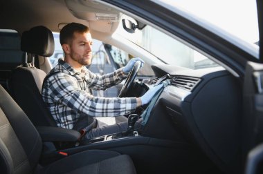 Araba yıkama ve araba yıkama konsepti. Genç bir adam, oto yıkama işçisi, koruyucu lastik eldiven giyiyor, arabanın içini temizliyor..