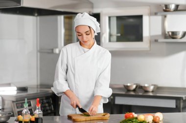 Yemek ve yemek konsepti. Gülümseyen kadın şef, sebze doğrayan aşçı..