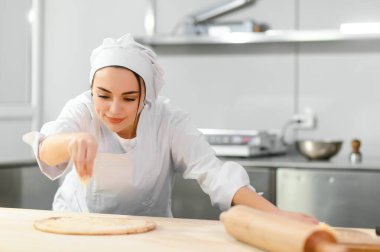 Kadın şef pizza üzerine peynir serper, restoran mutfağı....