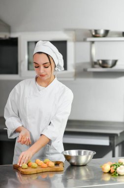 Güzel bir kadın şef bir restoranın mutfağında falafel pişirir..