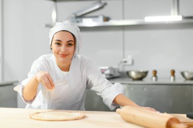 Kadın şef pizza üzerine peynir serper, restoran mutfağı....