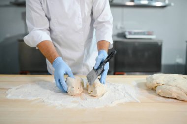 Erkek bir aşçı mutfakta hamur karıştırıyor. Çeşitli yarı bitmiş ürünlerin üretimi.