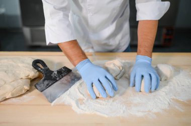 Erkek bir aşçı mutfakta hamur karıştırıyor. Çeşitli yarı bitmiş ürünlerin üretimi.