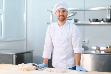 Erkek bir aşçı mutfakta hamur karıştırıyor. Çeşitli yarı bitmiş ürünlerin üretimi.