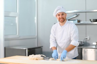 Erkek bir aşçı mutfakta hamur karıştırıyor. Çeşitli yarı bitmiş ürünlerin üretimi.