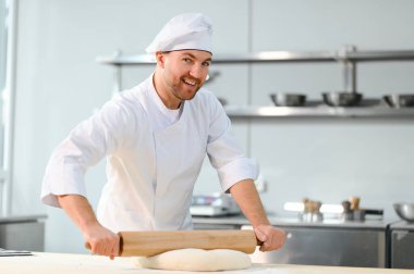 Erkek bir aşçı mutfakta hamur karıştırıyor. Çeşitli yarı bitmiş ürünlerin üretimi.