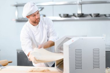 İşine odaklan. Makarna makinesinde hamuru yuvarlayan yakışıklı şef..