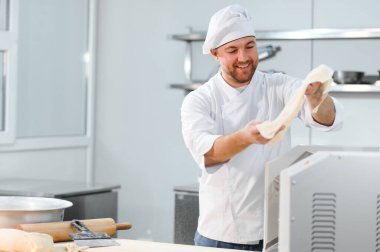 İşine odaklan. Makarna makinesinde hamuru yuvarlayan yakışıklı şef..