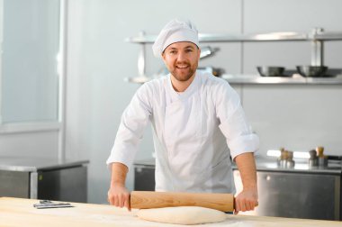 Genç aşçı, profesyonel mutfakta hamur yoğurur. Yarı bitmiş ürünler kavramı.