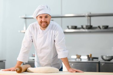 Fırında merdaneyle çalışırken, erkek aşçı hamurdan merdaneli ince düz pastalar yapar..