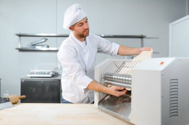 İşine odaklan. Makarna makinesinde hamuru yuvarlayan yakışıklı şef..