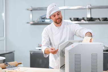 İşine odaklan. Makarna makinesinde hamuru yuvarlayan yakışıklı şef..