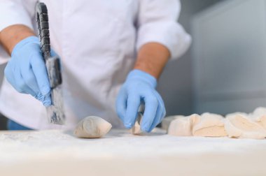 Genç aşçı, profesyonel mutfakta hamur yoğurur. Yarı bitmiş ürünler kavramı.