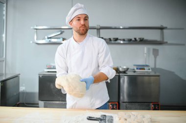 Genç aşçı, profesyonel mutfakta hamur yoğurur. Yarı bitmiş ürünler kavramı.