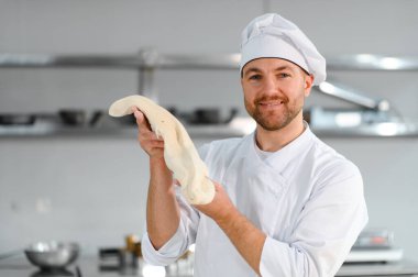 Genç aşçı, profesyonel mutfakta hamur yoğurur. Yarı bitmiş ürünler kavramı.