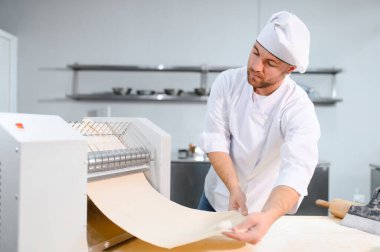 İşine odaklan. Makarna makinesinde hamuru yuvarlayan yakışıklı şef..