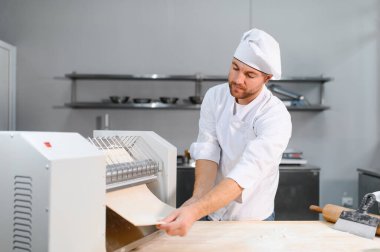 İşine odaklan. Makarna makinesinde hamuru yuvarlayan yakışıklı şef..