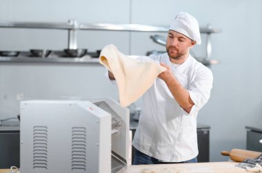 İşine odaklan. Makarna makinesinde hamuru yuvarlayan yakışıklı şef..