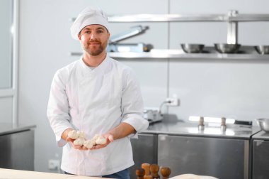 Profesyonel mutfakta khinkali yapan yakışıklı bir aşçı. Yarı bitmiş ürünler kavramı