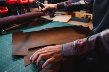 Terzi turtası farklı rulo tutuyor. Doğal kahverengi deri, atölyede tekstil ile çalışıyor. Sanayi Sanayi Sanayi İşletme Ustası.